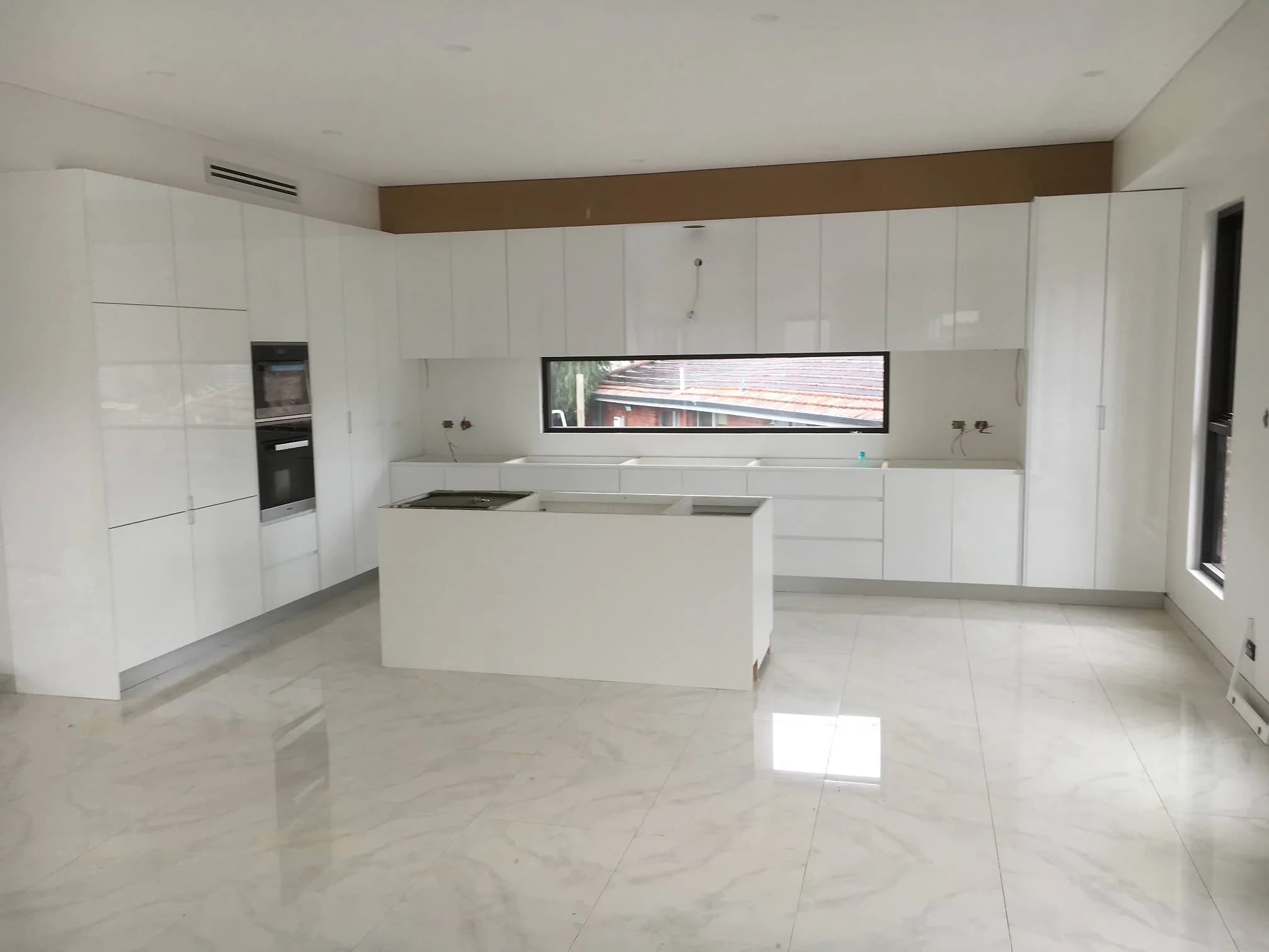 High-gloss white kitchen with full-height cabinetry and a marble-look waterfall island by H&R Kitchens