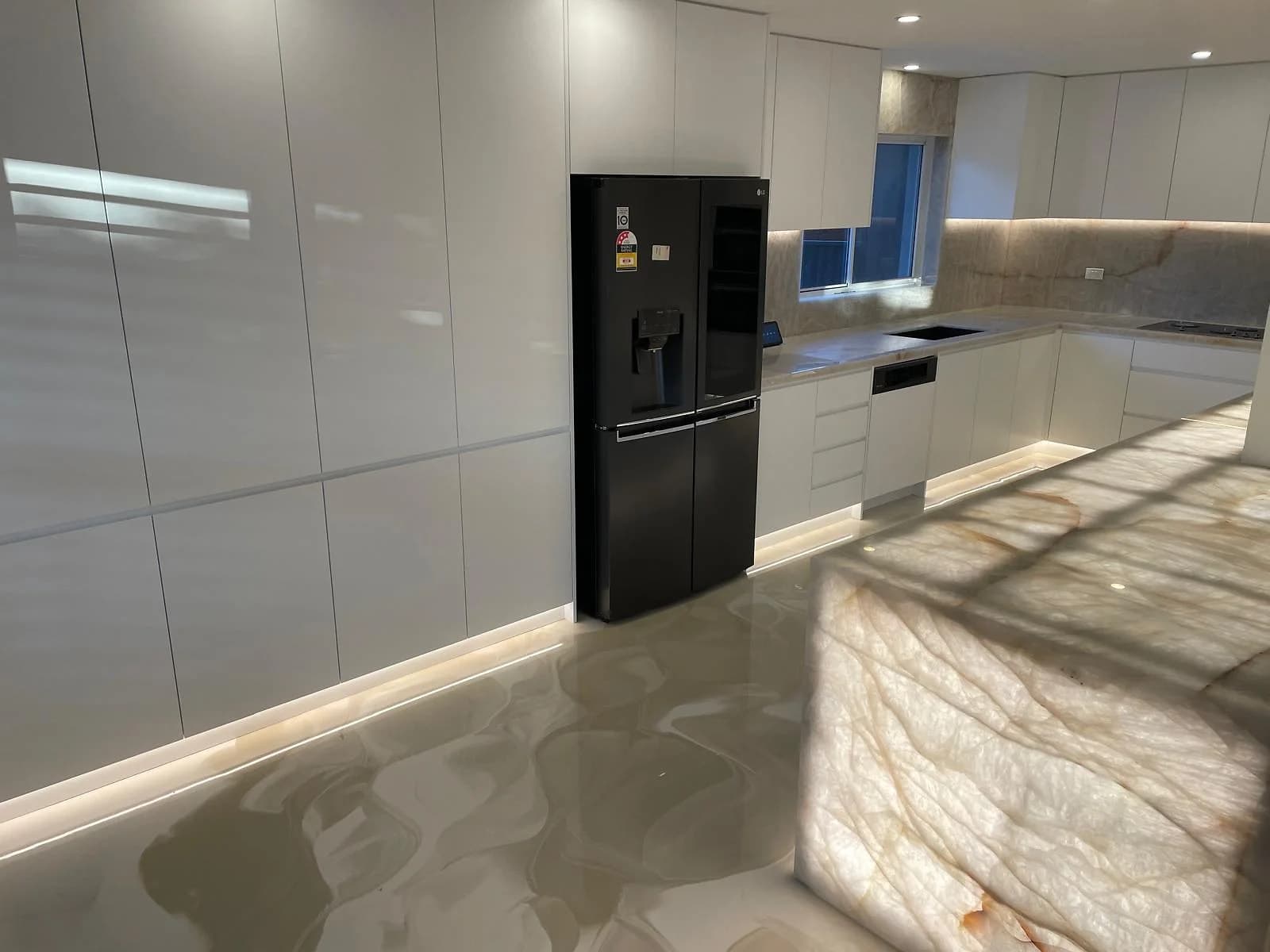 Gloss white handleless kitchen with a translucent illuminated stone island by H&R Kitchens