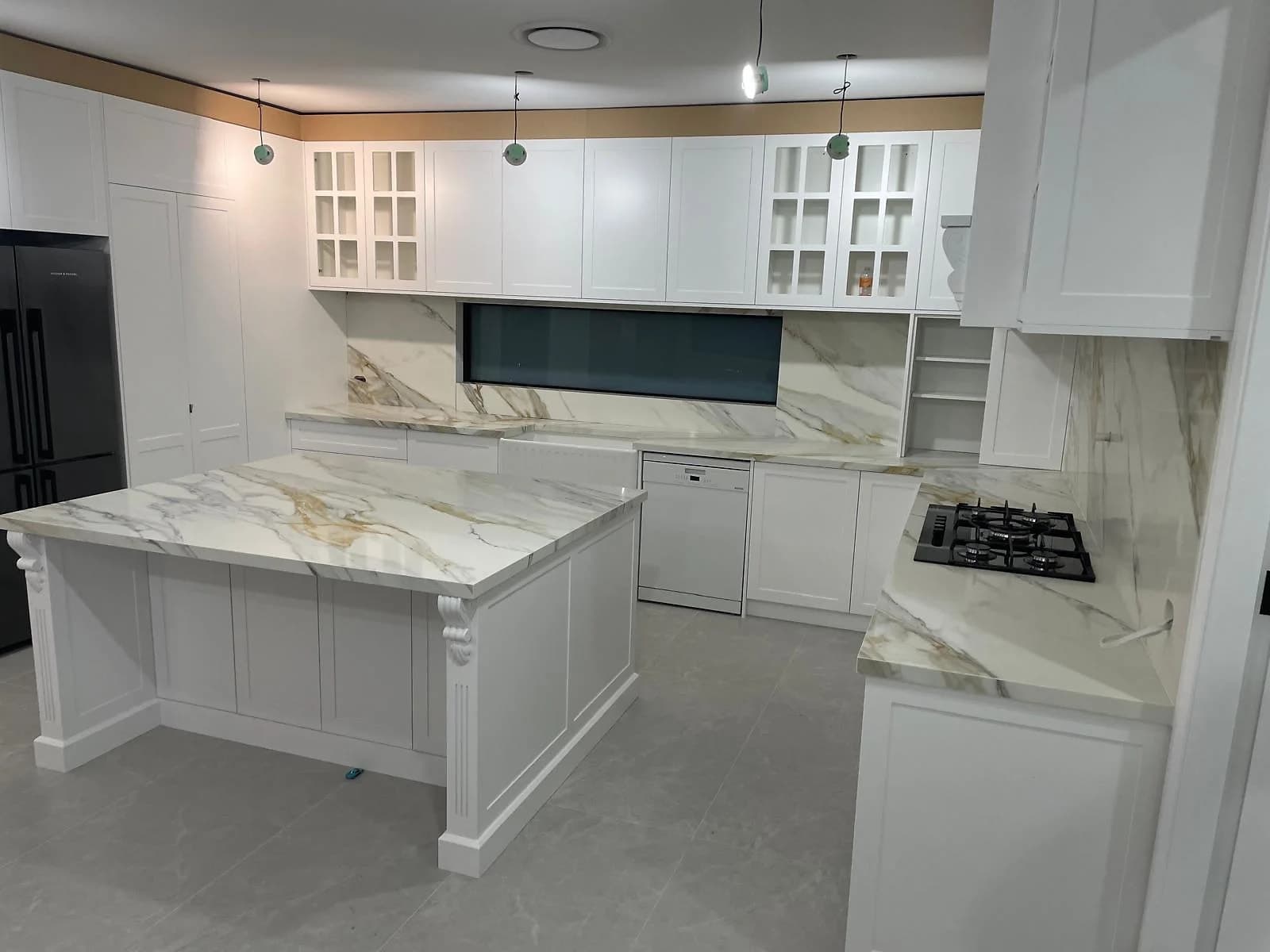 Ornate white shaker kitchen with a dark-framed window and marble-look island by H&R Kitchens