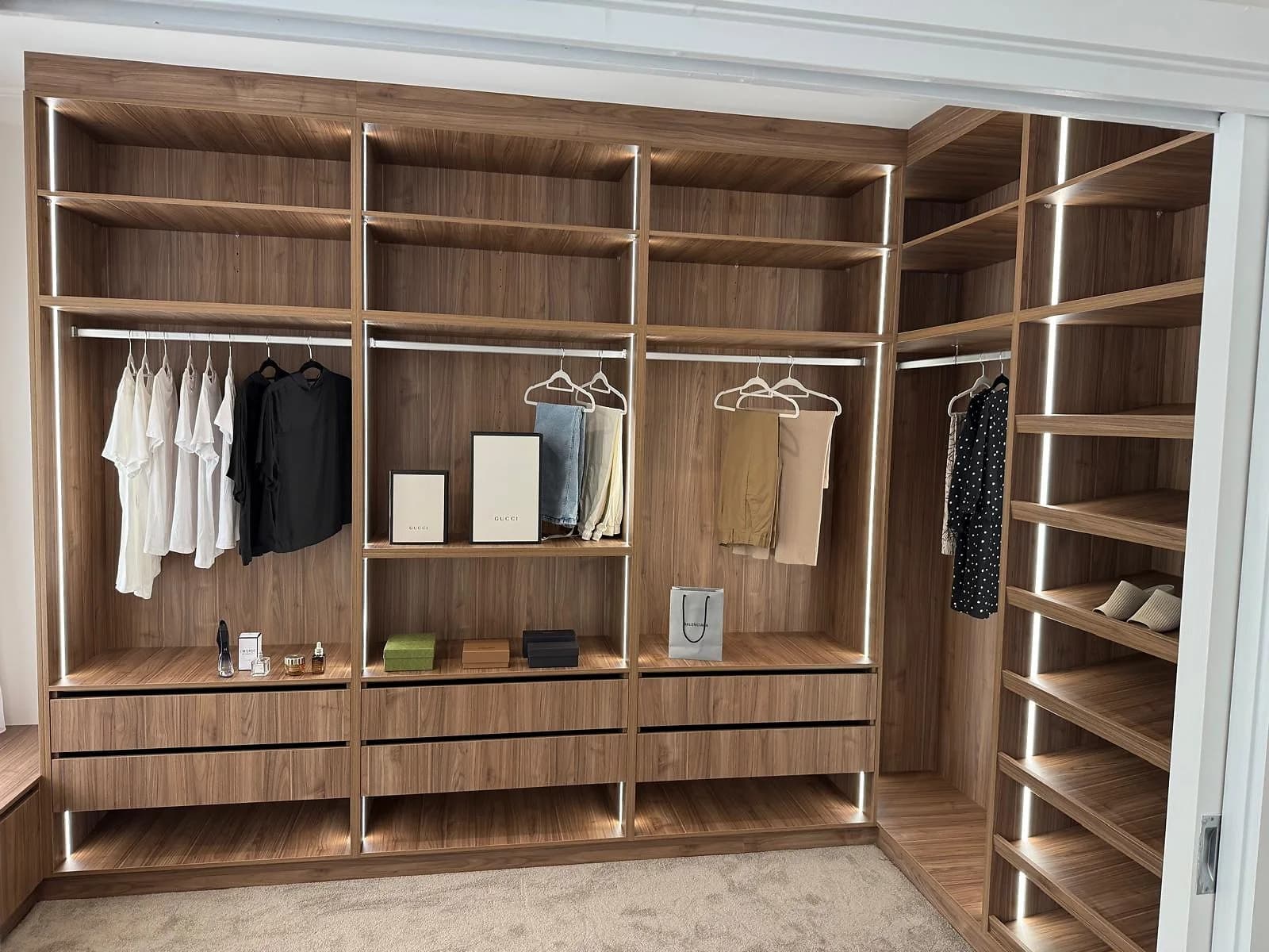 Timber-look walk-in wardrobe with fitted hanging, drawers, shelving and display storage by H&R Kitchens