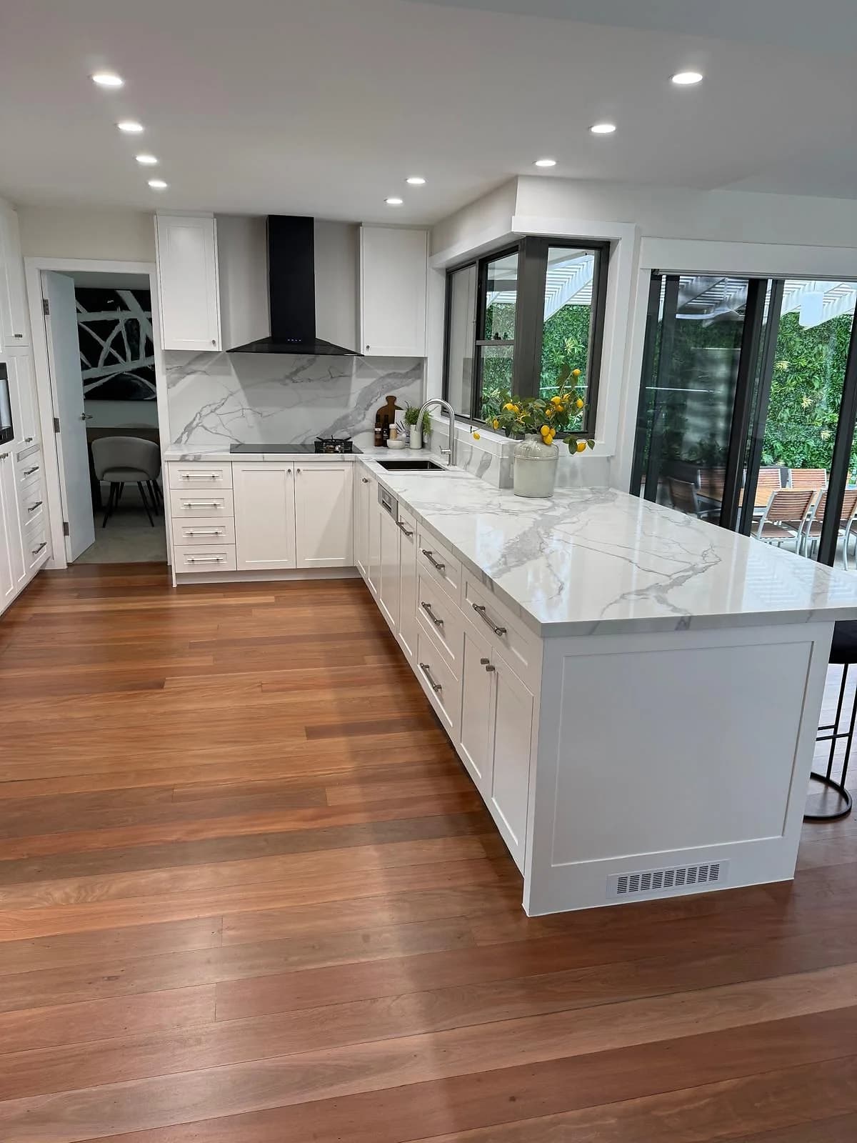 White shaker kitchen with marble-look benchtops, island cabinetry and timber flooring, by H&R Kitchens