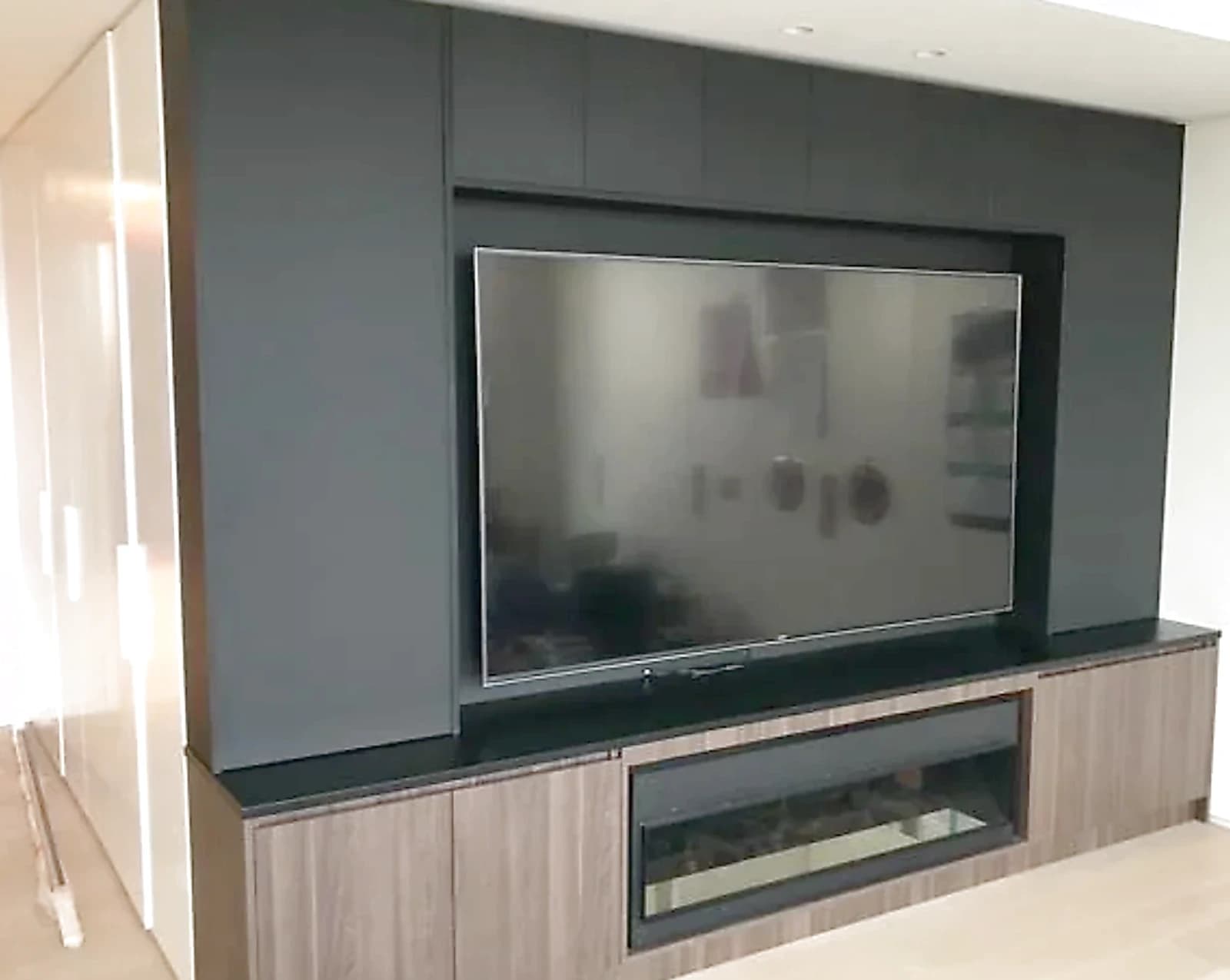 Custom entertainment wall joinery with storage and display shelving by H&R Kitchens