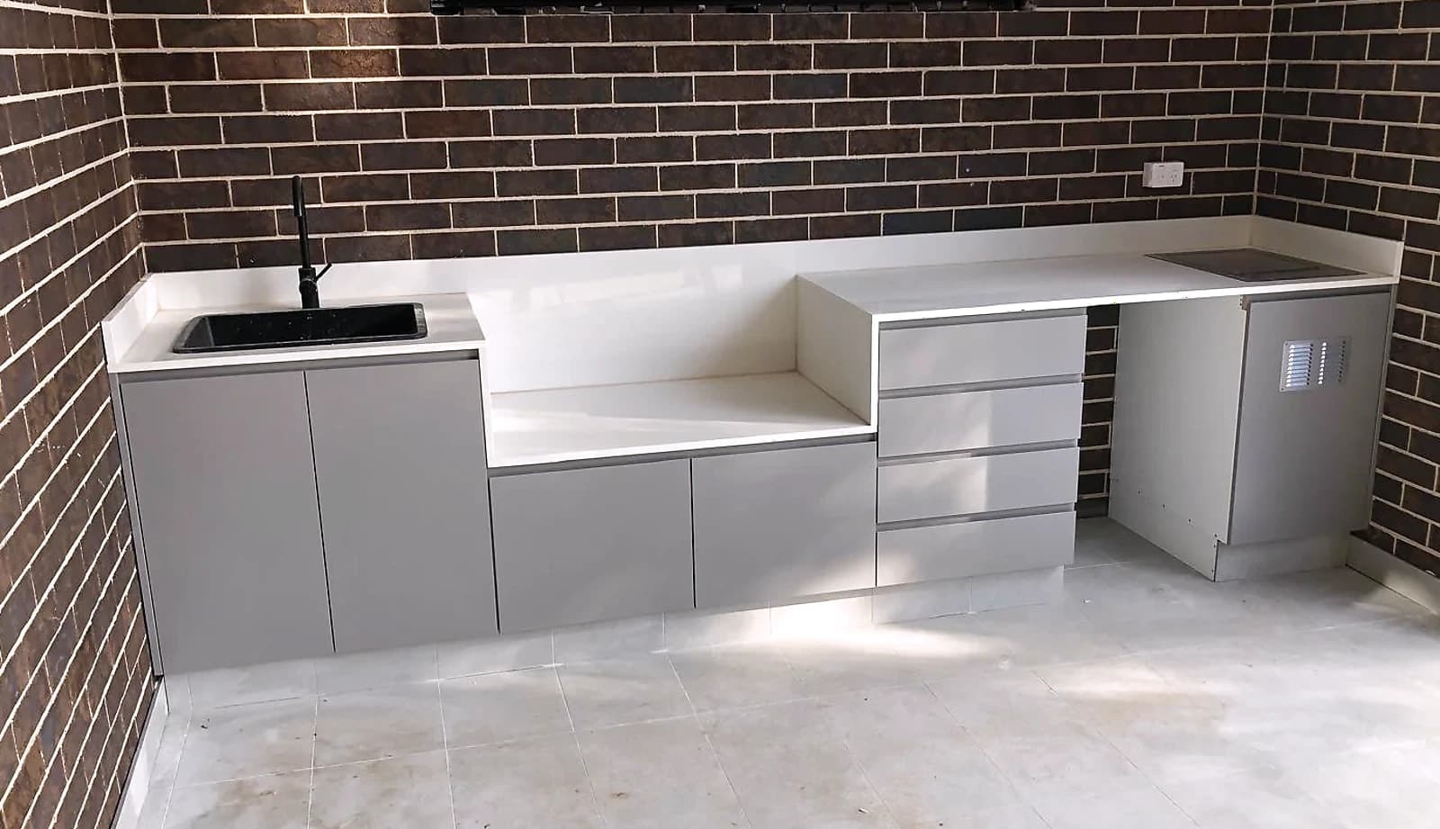Custom laundry with white shaker cabinetry, a marble-look benchtop, a finger-tile splashback, a side-by-side washer and dryer and a black undermount sink, by H&R Kitchens