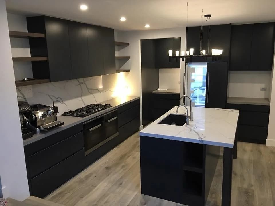 Black kitchen cabinetry with a marble-look benchtop and splashback, by H&R Kitchens