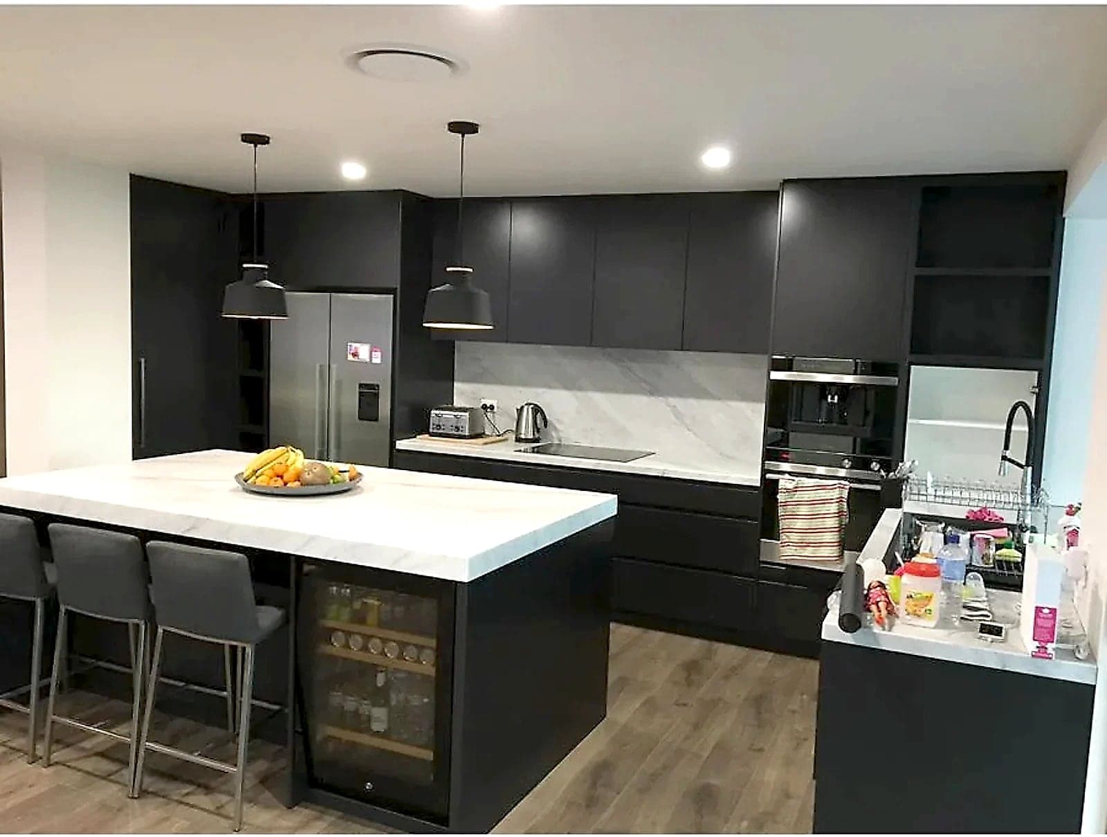 Charcoal handleless kitchen with a marble-look island, a wine fridge and open shelving by H&R Kitchens