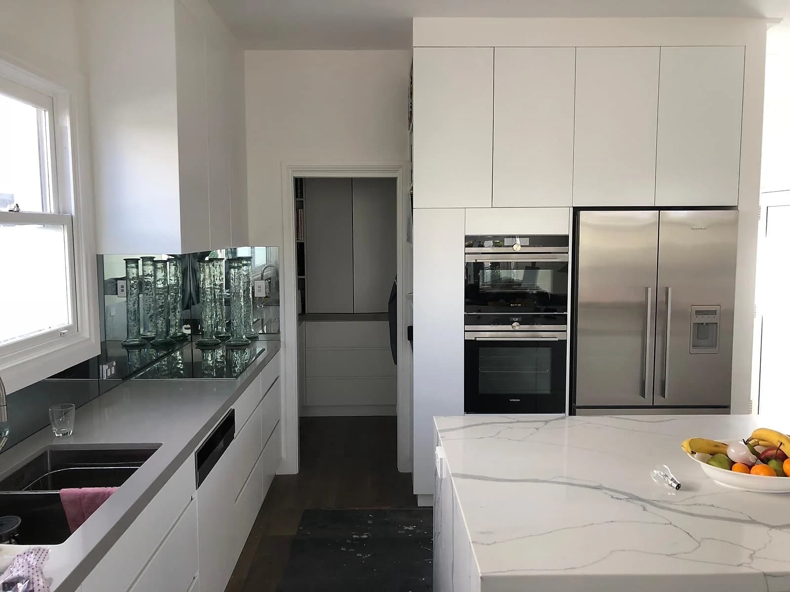 Tall kitchen and pantry cabinetry with integrated appliances and a secondary preparation area by H&R Kitchens