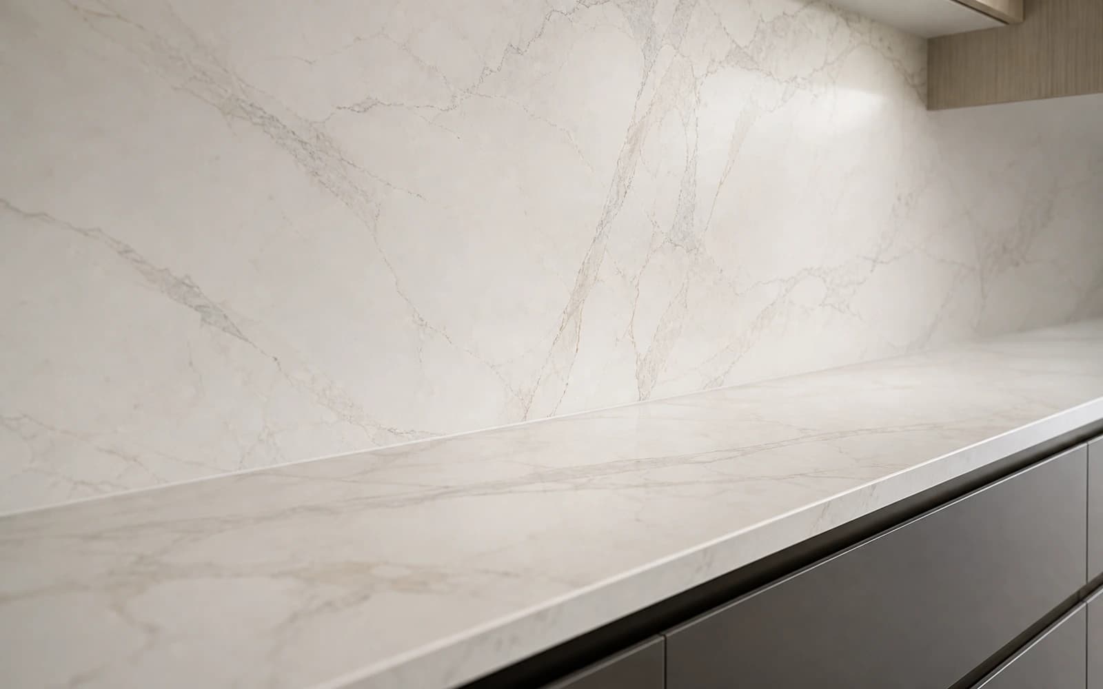 Close-up of a Calacatta marble-look stone splashback running full height above a matching stone benchtop, by H&R Kitchens